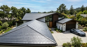 A modern home featuring a sleek Tesla Solar Roof with dark, textured glass tiles.