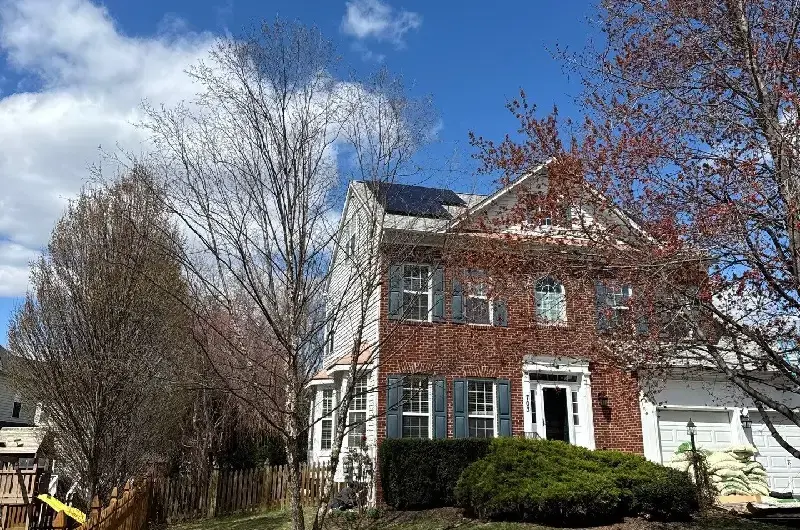 A professional Solar Panel Installation on a red brick residential home under a bright blue sky
